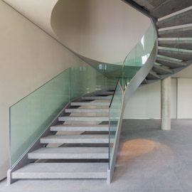 escada curva residencial com guarda-corpo de vidro